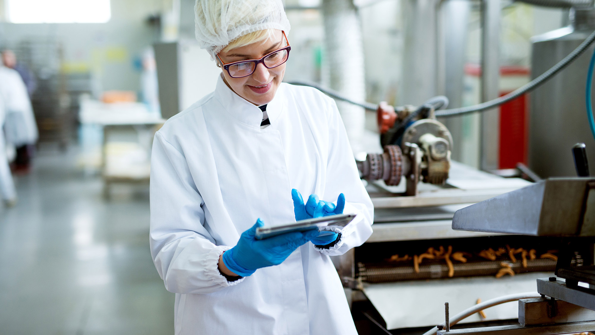 A woman wearing a white lab coat is engaged with a tablet, showcasing her work in a laboratory environment.